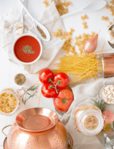 different types of pasta, tomatoes and other ingredients and containers