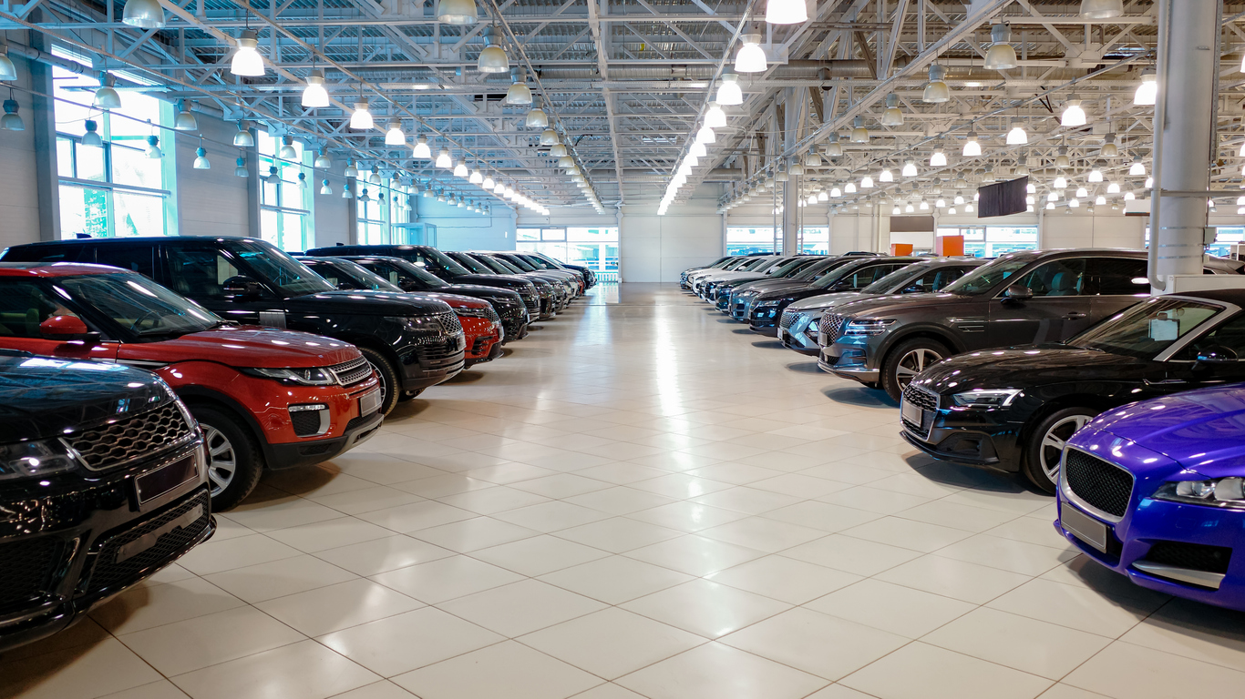 Car dealership showroom interior with rows of new vehicles.