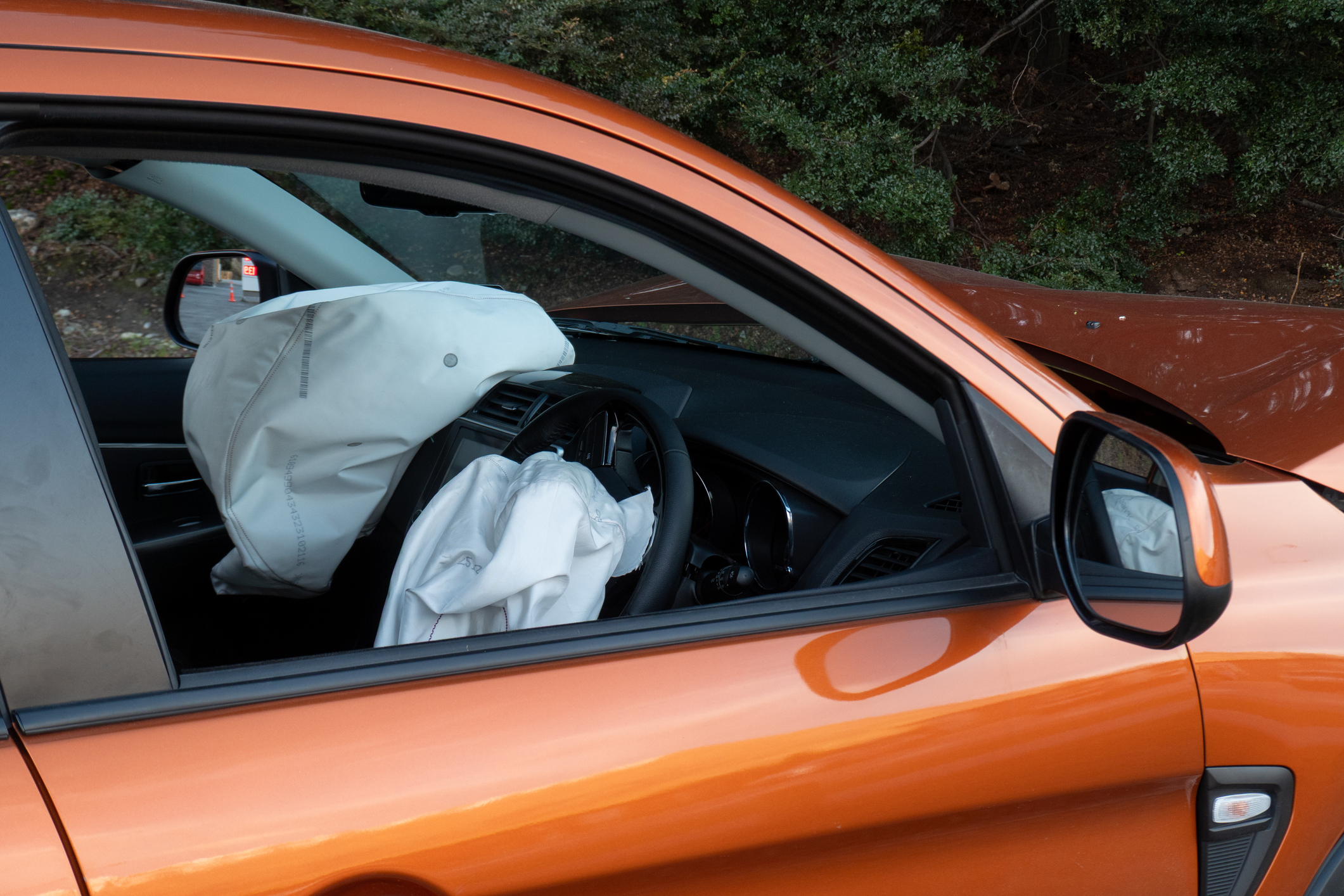 Looking through the open passenger window of orange car with airbags deployed
